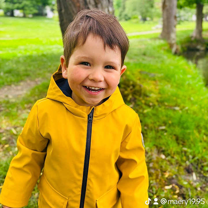 Pablo participe au concours pour gagner de l'argent avec cette photo : casual_clothing, child, childhood, cute, daylight, face, fun, grass, greenery, happy, nature, outdoor, park, person, photography, portrait, smiling, tree, yellow_raincoat, young