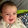baby, smiling, infant, face, onesie, hot_air_balloon_pattern, blanket, pillow, happy, cute, child, portrait, indoors, closeup, skin, head, eyebrows, mouth, furniture, comfort