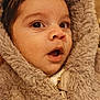 baby, child, face, fur, hood, coat, warm_clothing, curious, wide_eyes, close_up, portrait, cute, expression, winter_wear, soft_texture, brown, skin, eyelashes, mouth_open, infant