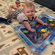 Kaïs a rejoint le concours — aidez-le/la à gagner de superbes lots ! baby, child, play_mat, toy, indoor, floor, infant, smiling, crawling, water_toy, colorful, soft_lighting, playtime, cute, home, furniture, floor_mat, animal_toys, person, happy