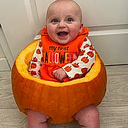 Niamh is registered to the contest to win money with this photo: baby, pumpkin, halloween, orange, smile, child, holiday, costume, festive, cute, indoors, floor, door, celebration, happy, sitting, person, head, face, clothing