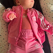 Paola a rejoint le concours — aidez-le/la à gagner de superbes lots ! baby, infant, pink_clothing, adidas, jacket, pants, sleeping, cushion, patterned_background, indoor, child, person, cute, resting, soft_light, casual, relaxed, small_person, face, hand