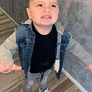 Kelio a rejoint le concours — aidez-le/la à gagner de superbes lots ! black_shirt, casual_clothing, child, denim_jacket, expression, fashion, flooring, gray_pants, gray_wall, happy, indoor, motion, person, portrait, short_hair, smile, sneakers, standing, wooden_floor, young_boy