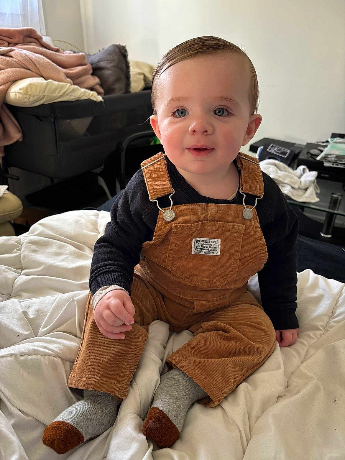 Naëlyo participe au concours pour gagner de l'argent avec cette photo : baby, child, toddler, overalls, corduroy, socks, blanket, bed, indoor, portrait, smile, blue_eyes, hair, hand, cute, living_room, clothing, sitting, close_up, nursery