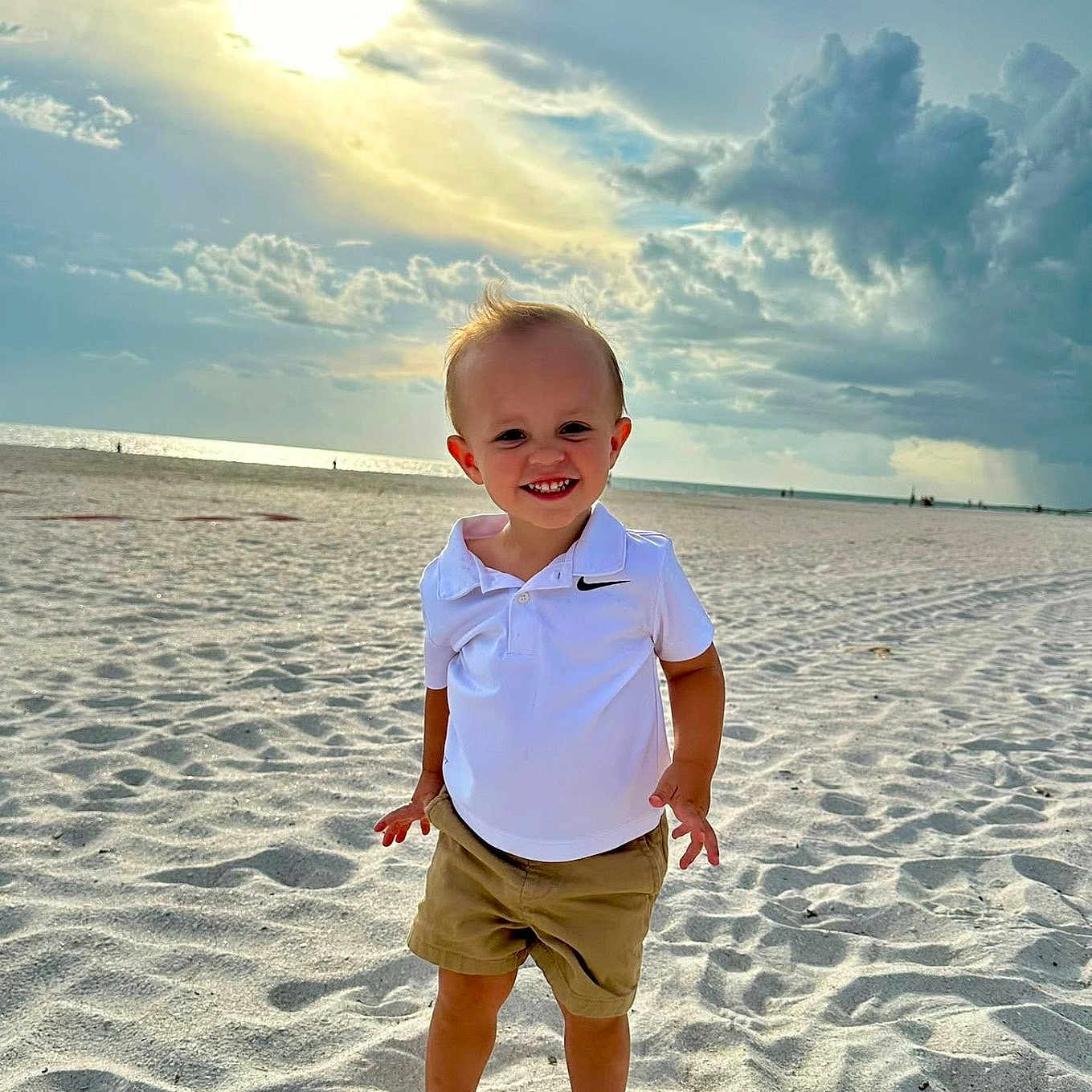 Tate is registered to the contest to win money with this photo: barefoot, beach, casual_clothing, child, clouds, happy, nature, outdoor, polo_shirt, portrait, sand, shorts, sky, smile, standing, summer, sun, sunlight, toddler, vacation