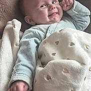 Romy participe au concours pour gagner de l'argent avec cette photo : baby, blanket, blue_clothing, child, comfort, cozy, cute, cute_expression, face, hand, heart_pattern, indoors, infant, lying_down, plush, portrait, resting, smiling, soft_texture, warm