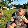 Grayson is registered to the contest to win money with this photo: baby, child, onesie, winnie_the_pooh, car_seat, outdoor, grass, tree, sunlight, suburban, curious, infant, foot, hand, greenery, daylight, person, cute, seat, parked