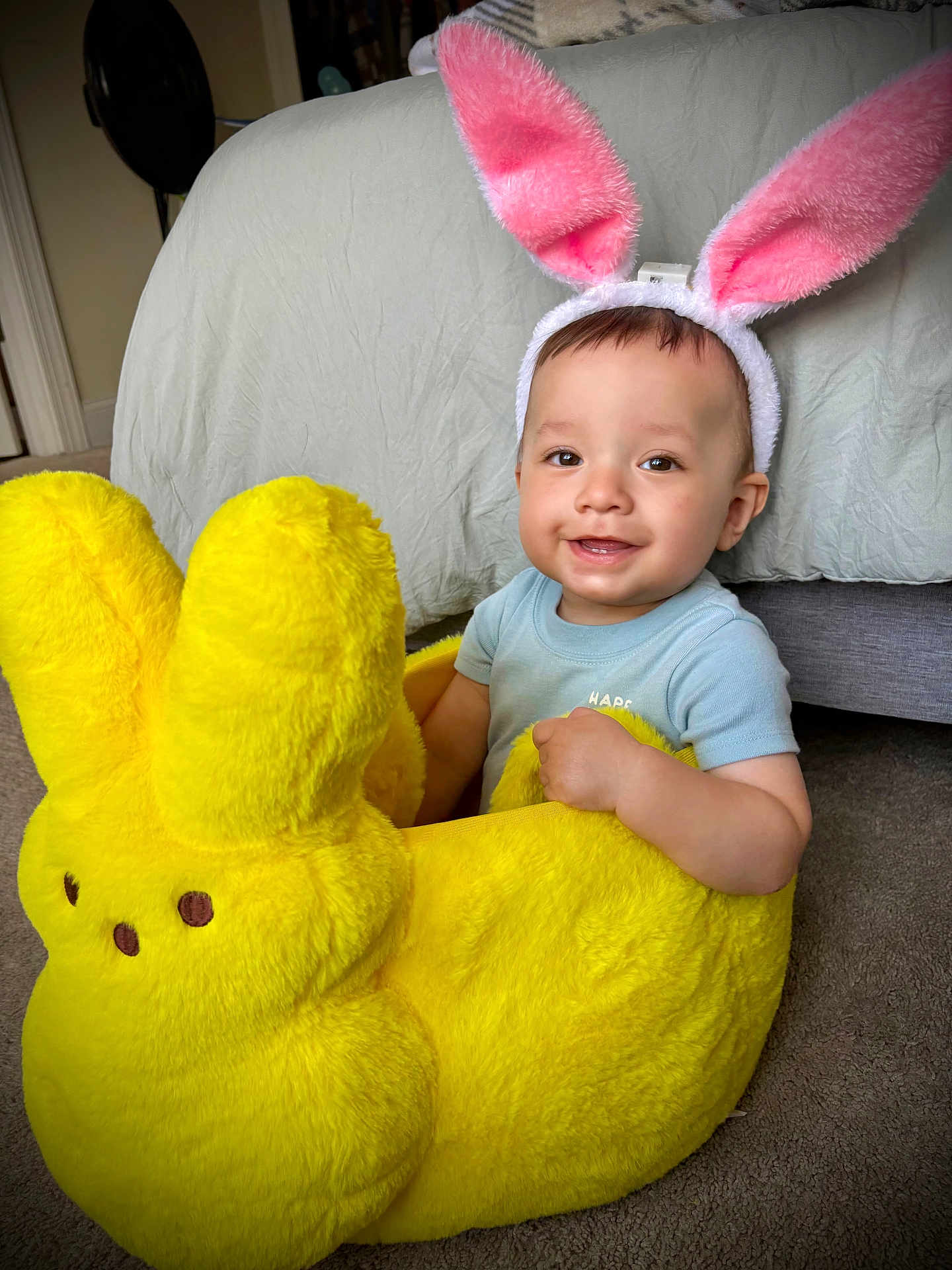 Grayson joined the competition — help win amazing prizes! toddler, child, bunny_ears, plush_toy, yellow, smiling, indoor, carpet, bed, cute, playful, soft_toy, baby, headband, fun, happy, person, home, comfort, toy