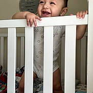 Grayson is registered to the contest to win money with this photo: baby, toddler, crib, smiling, happy, indoors, nursery, milestone_board, blanket, clothing, person, child, hand, face, furniture, home, cute, infant, standing, tooth