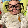 baby, glasses, face, child, onesie, moon, stars, cushion, green, white, pattern, clothing, cute, smile, indoor, infant, chubby_cheeks, food_stains, comfort, portrait