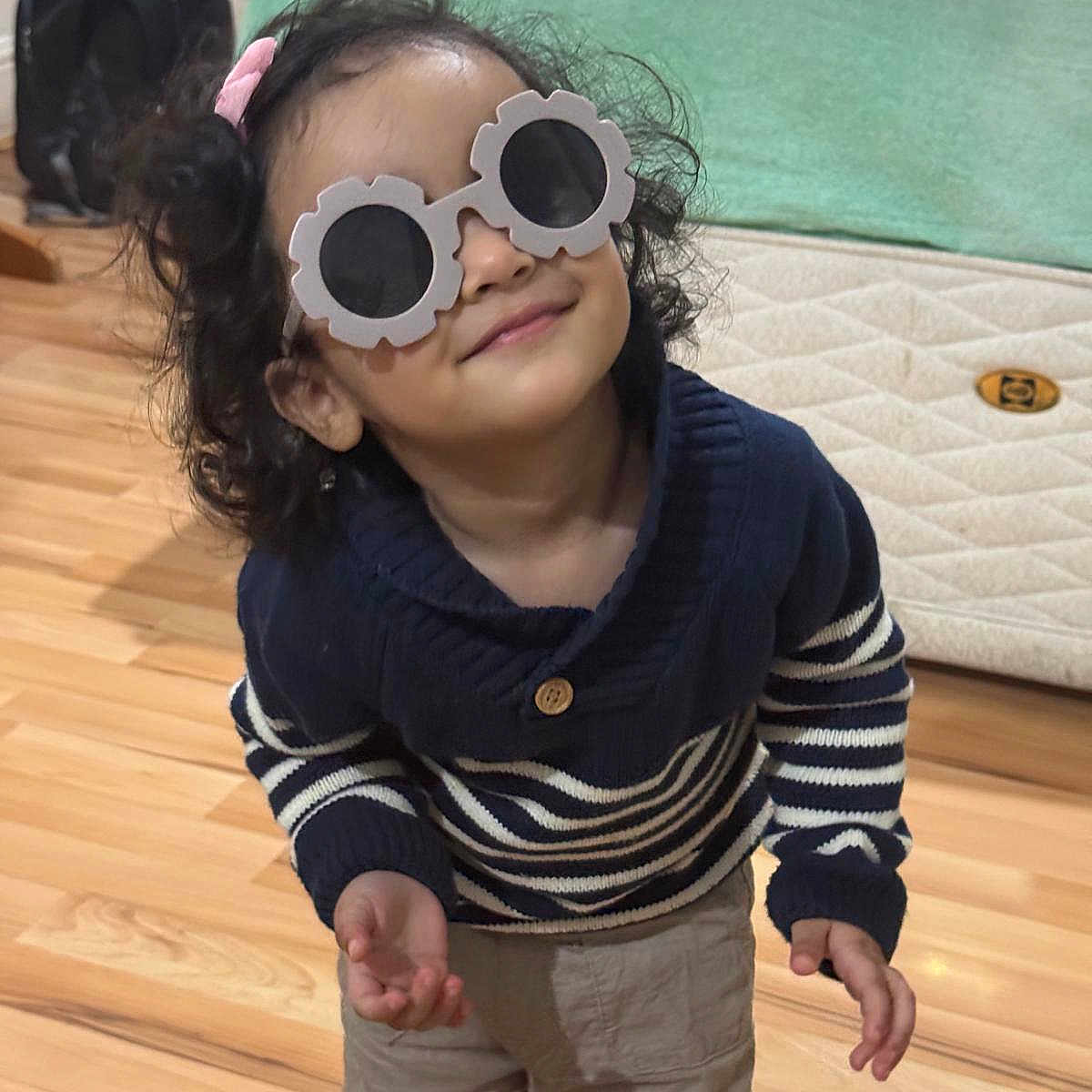 Anand joined the competition — help win amazing prizes! backpack, bed, casual, child, clothing, curly_hair, cute, funny_glasses, glasses, home, indoor, person, playful, portrait, smile, striped_sweater, sunglasses, toddler, wooden_floor, young_child