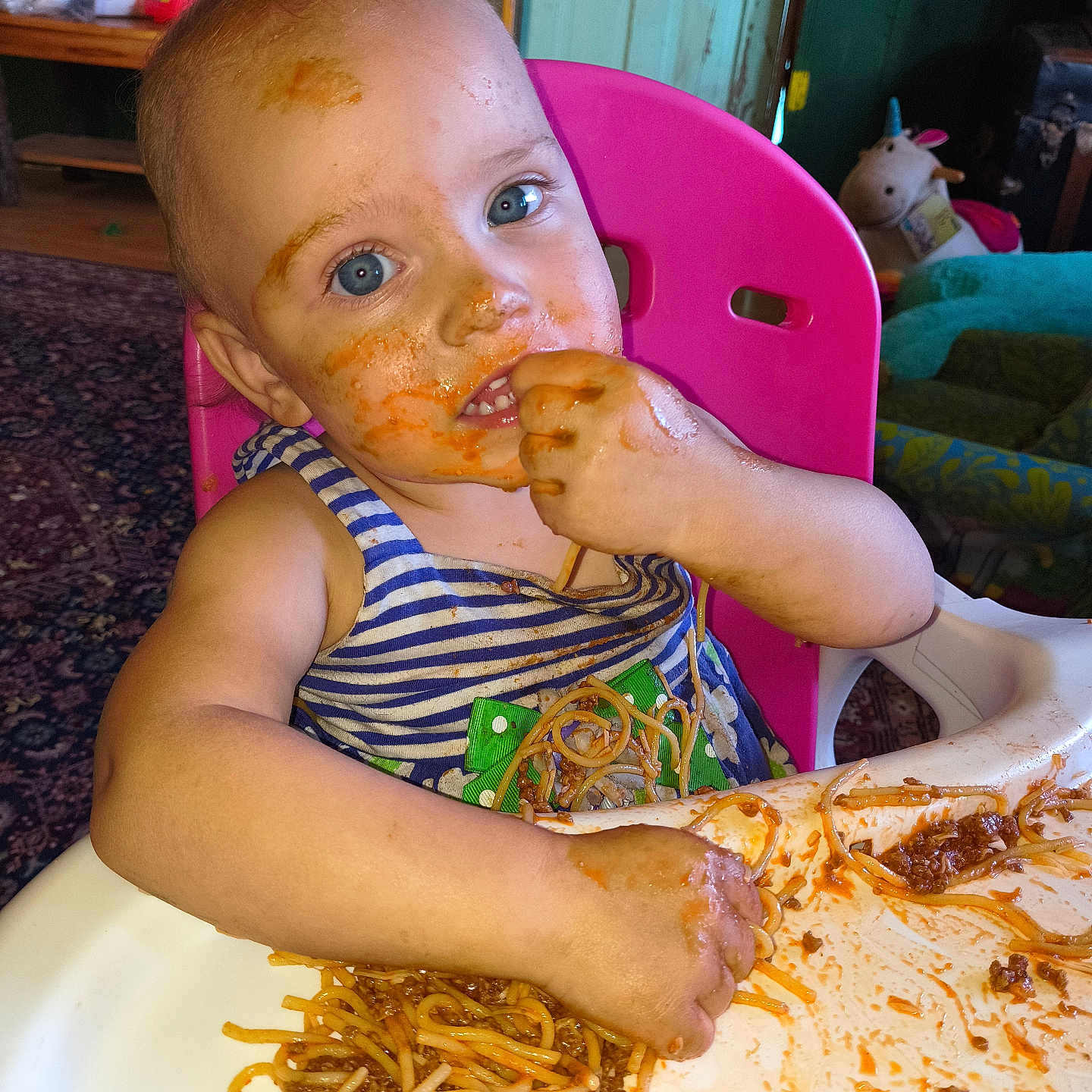 Astraea is registered to the contest to win money with this photo: baby, blue_eyes, child, clothing, cute, dining, expression, face_paint, food, hair, hands, high_chair, indoor, meal, messy, pink_chair, plate, spaghetti, table, tongue_out