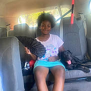Khimora is registered to the contest to win money with this photo: child, girl, afro_hair, black_dog, dog, car_interior, car_seat, fan, hello_kitty, tshirt, skirt, sunlight, window, seatbelt, tongue_out, pet, smiling, summer, casual_clothing, relaxed