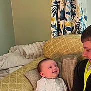 Tommy joined the competition — help win amazing prizes! baby, child, smiling, couch, cushion, person, indoor, curtain, pattern, clothing, baby_clothes, happy, face, infant, young_man, seated, home, interaction, family, relaxed