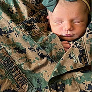 Sutton joined the competition — help win amazing prizes! baby, newborn, sleeping, camouflage, military_jacket, bow, headband, face, infant, peaceful, closeup, soft_skin, clothing, portrait, cute, hands, fabric, texture, camouflage_pattern, toddler