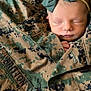 baby, newborn, sleeping, camouflage, military_jacket, bow, headband, face, infant, peaceful, closeup, soft_skin, clothing, portrait, cute, hands, fabric, texture, camouflage_pattern, toddler