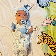 Luka is registered to the contest to win money with this photo: baby, infant, pajamas, mittens, pacifier, hat, blanket, animal_print, tiger, elephant, pig, dragonfly, striped_socks, lying_down, cute, child, indoors, soft_texture, colorful, portrait