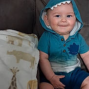 Elijah joined the competition — help win amazing prizes! baby, child, smiling, portrait, seated, indoor, chair, hood, shark_hood, turquoise_clothing, blanket, giraffe_pattern, couch, infant, face, eyes, hands, legs, cozy, photography