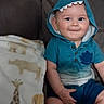 baby, child, smiling, portrait, seated, indoor, chair, hood, shark_hood, turquoise_clothing, blanket, giraffe_pattern, couch, infant, face, eyes, hands, legs, cozy, photography