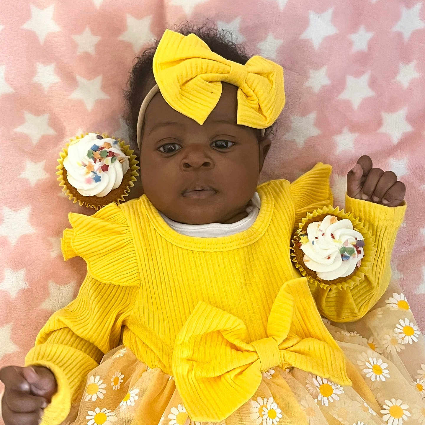 Omoize is registered to the contest to win money with this photo: baby, blanket, bow, celebration, child, cupcake, cute, floral_pattern, happy, headband, infant, pink_background, portrait, smiling, soft_texture, sprinkles, stars, sweet, tutu_skirt, yellow_dress