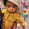 accessories, baby, child, clothing, colorful, cute, dress, face, floral, hair_bows, hand, hat, holding, indoor, infant, person, portrait, retail, shopping, store