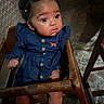 baby, child, clothing, curly_hair, cute, denim_dress, expression, eyes, face, floor, hair_clips, high_chair, indoor, infant, person, portrait, seated, small_hands, socks, wooden_furniture
