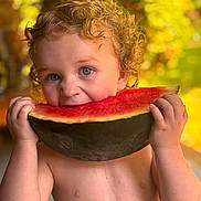 Asher is registered to the contest to win money with this photo: toddler, child, watermelon, fruit, summer, outdoor, curly_hair, blue_eyes, bare_chest, juice, eating, happy, cute, portrait, food, close_up, natural_light, greenery, warm_tones, fun