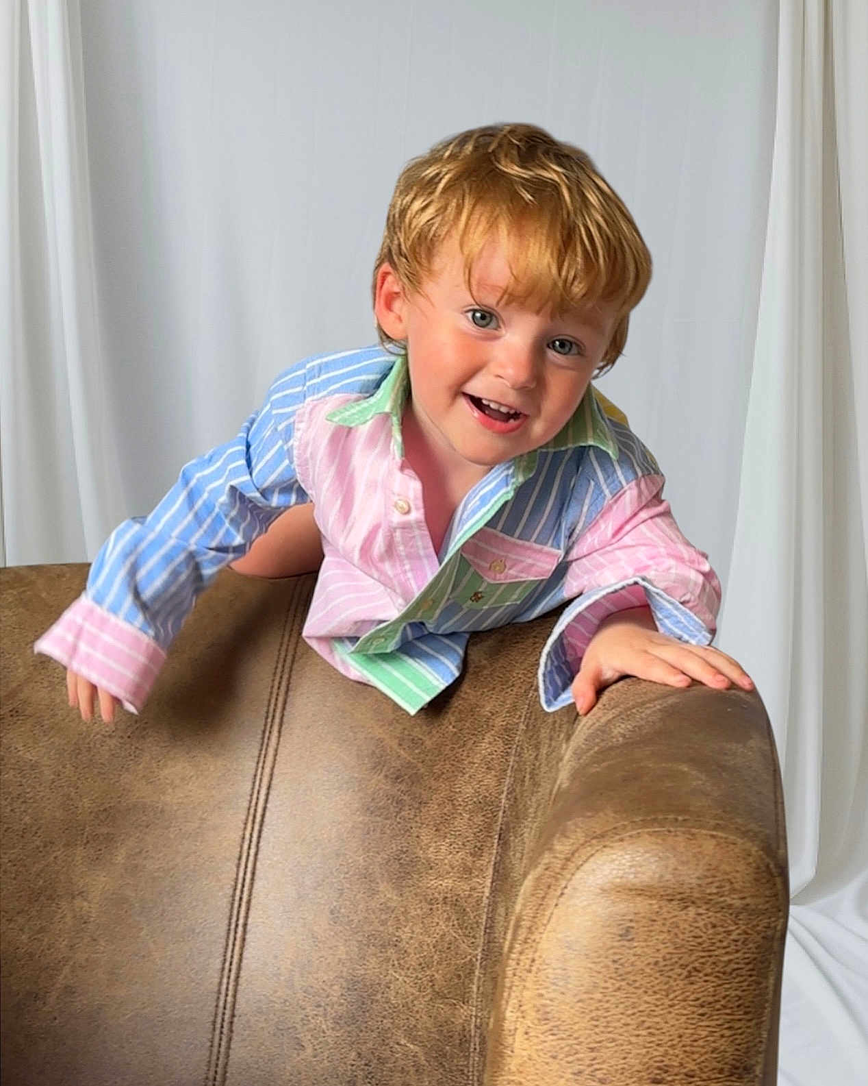 Jasper joined the competition — help win amazing prizes! child, toddler, smiling, indoor, leather_chair, striped_shirt, blond_hair, happy, portrait, playful, curtain, person, casual_clothing, young_child, cute, face, hand, furniture, bright_eyes, candid