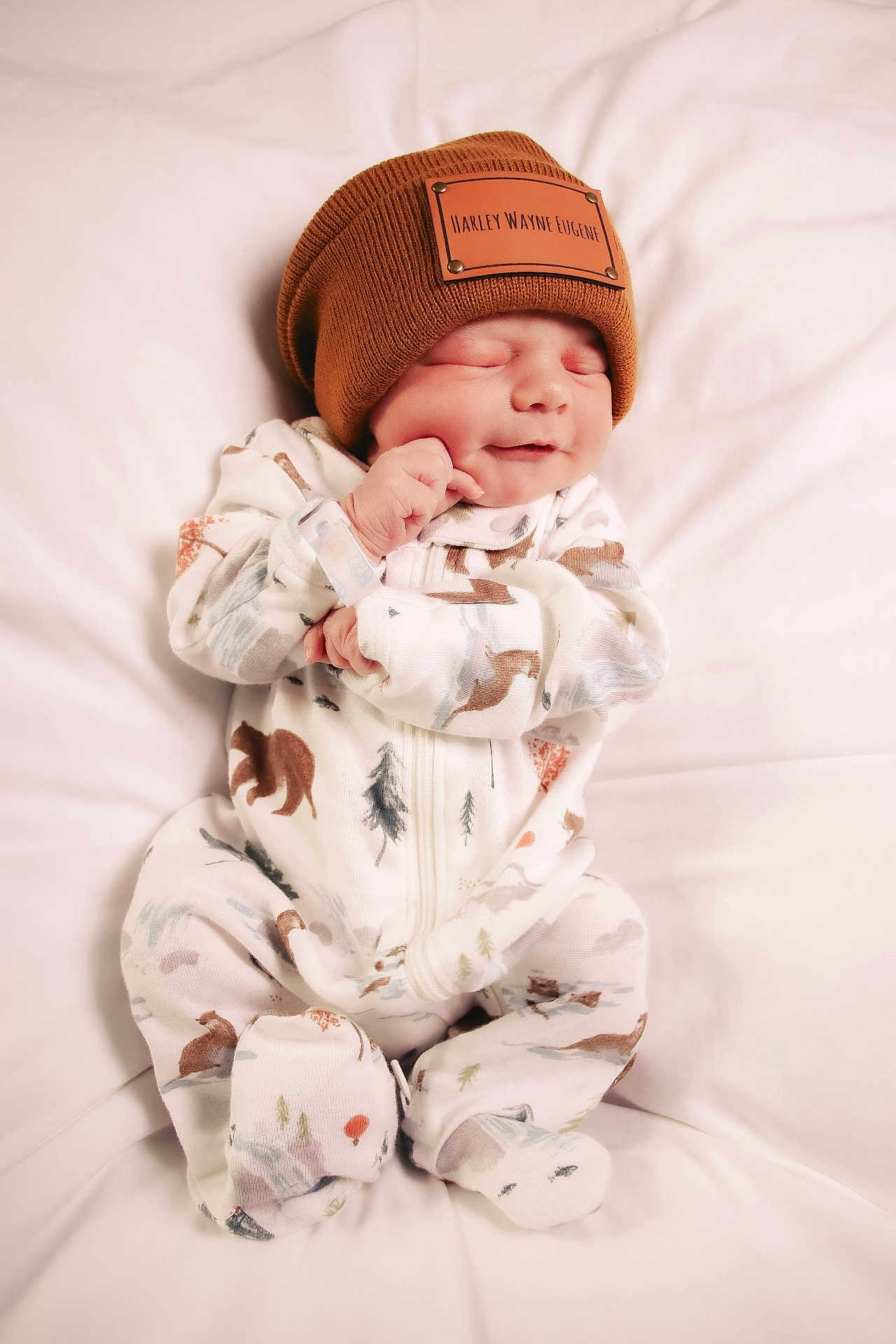 Harley joined the competition — help win amazing prizes! baby, newborn, sleeping, beanie, hat, onesie, animal_pattern, white_background, soft, cute, peaceful, infant, clothing, resting, child, portrait, cozy, small, smile, hand