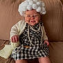 baby, child, costume, glasses, knitting, yarn, wool, pearls, plaid_dress, couch, smile, indoors, cute, funny, handmade, white_hair_wig, knitting_needles, cozy, sitting, portrait