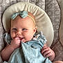 Emory is registered to the contest to win money with this photo: baby, infant, child, blue_dress, headband, bow, hand, fingers, cushion, seat, pattern, happy, smile, cheeks, skin, person, cute, indoors, portrait, relaxing