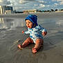 baby, child, beach, sand, water, swimsuit, hat, ocean, sunlight, clouds, reflection, sitting, smiling, outdoor, summer, vacation, nature, happy, toddler, play