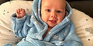 Brennus joined the competition — help win amazing prizes! baby, infant, smile, blue_bathrobe, cozy, fist, pillow, couch, happy, face, head, child, clothing, indoor, soft_texture, cute, portrait, newborn, sitting, warm