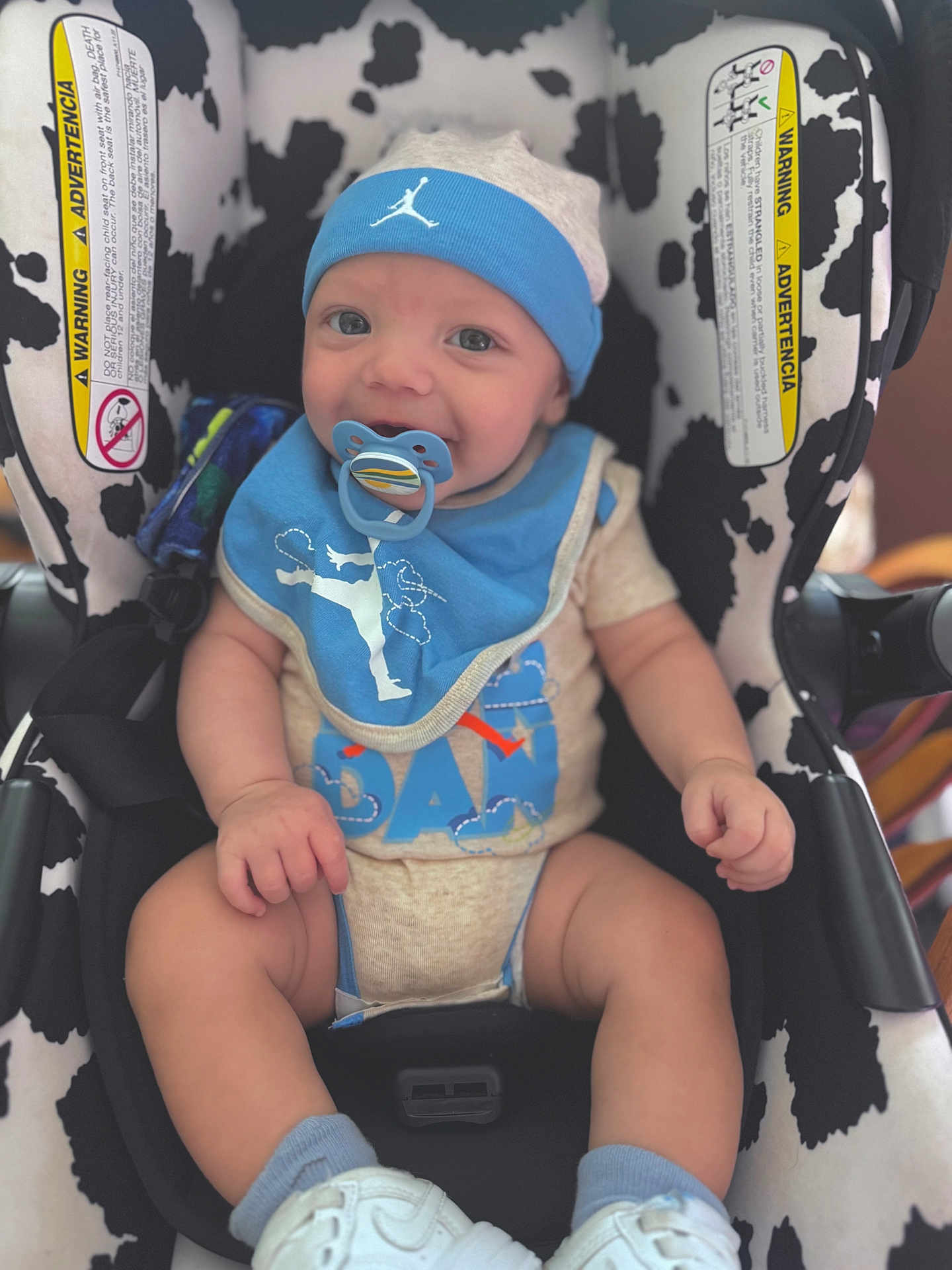 Dayden joined the competition — help win amazing prizes! baby, child, pacifier, car_seat, blue_bib, blue_hat, white_shoes, infant, smiling, sitting, clothing, footwear, baby_boy, cute, indoor, seat_belt, comfort, happy, closeup, human