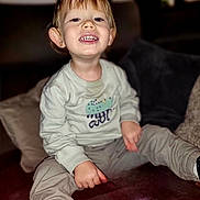 Tiago a rejoint le concours — aidez-le/la à gagner de superbes lots ! child, toddler, smiling, sitting, couch, clothing, happy, indoor, face, person, pants, shirt, footwear, furniture, portrait, young_child, casual, cozy, cute, playful