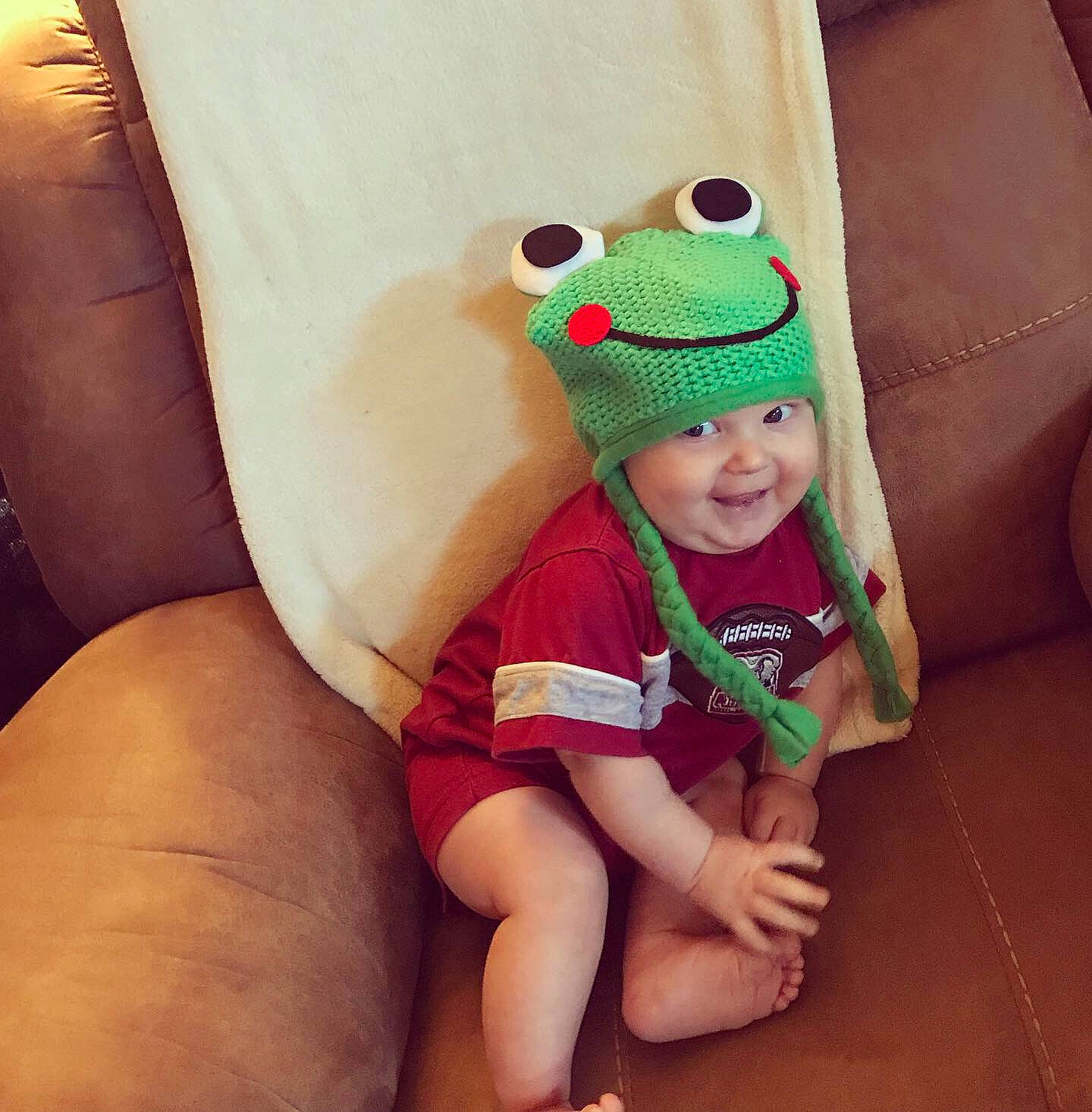 Baker is registered to the contest to win money with this photo: baby, beanie, cap, child, green, hand, headgear, headwear, joy, leg, person, smile, toddler