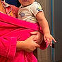 Tiberias joined the competition — help win amazing prizes! baby, child, indoor, person, holding, pink_robe, curious_expression, short_hair, toddler, clothing, hand, face, portrait, sleeve, doorway, floor, home, skin, smile, young