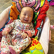 Penelope Reign is registered to the contest to win money with this photo: baby, infant, smiling, onesie, floral_pattern, blanket, baby_seat, happy, cute, indoors, floor_tiles, colorful, child, cozy, portrait, clothing, person, baby_girl, soft_toys, relaxing
