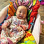 baby, infant, smiling, onesie, floral_pattern, blanket, baby_seat, happy, cute, indoors, floor_tiles, colorful, child, cozy, portrait, clothing, person, baby_girl, soft_toys, relaxing