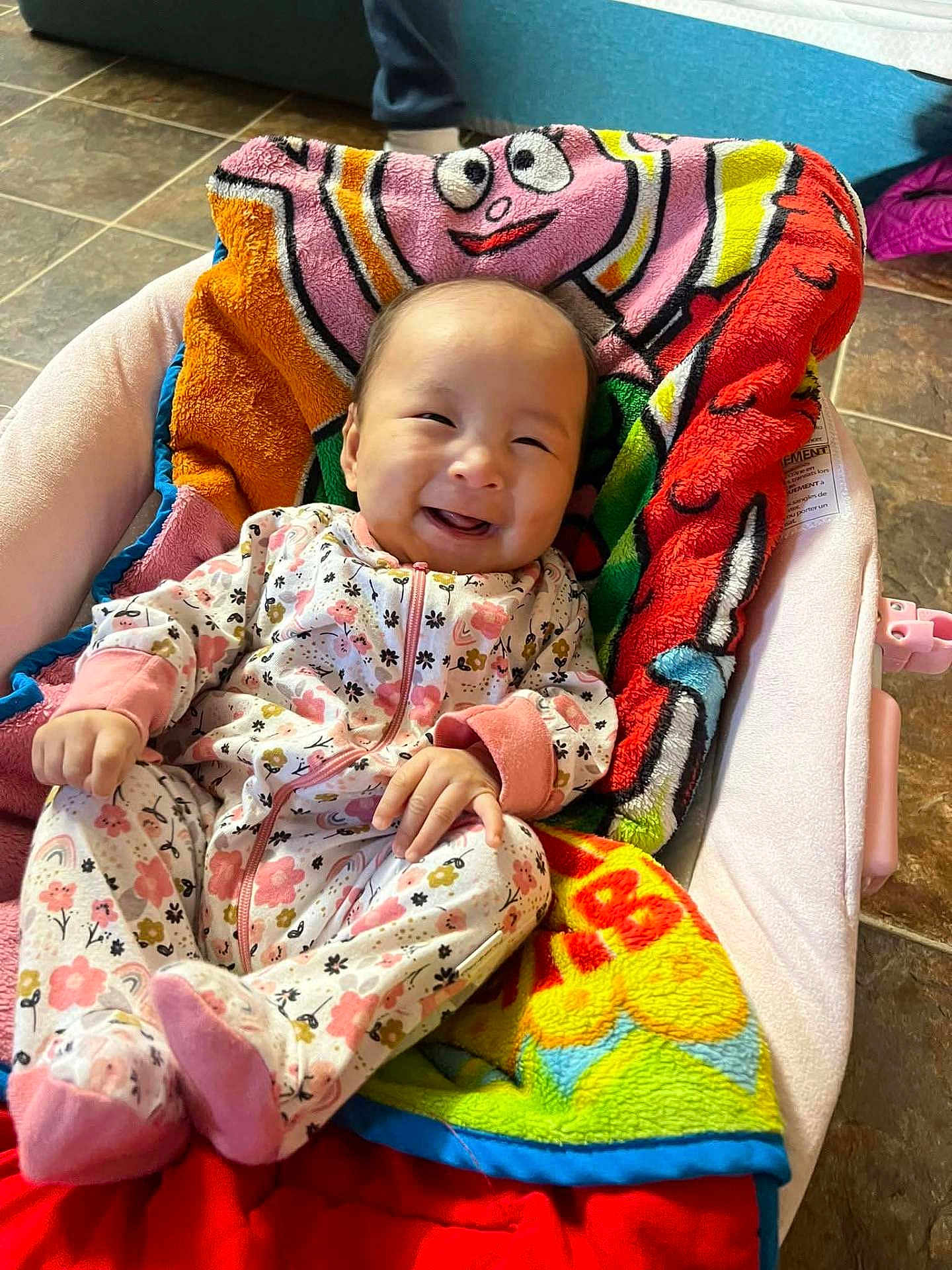 Penelope Reign is registered to the contest to win money with this photo: baby, infant, smiling, onesie, floral_pattern, blanket, baby_seat, happy, cute, indoors, floor_tiles, colorful, child, cozy, portrait, clothing, person, baby_girl, soft_toys, relaxing