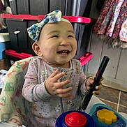Penelope is registered to the contest to win money with this photo: baby, child, smiling, headband, onesie, toy, walker, indoor, happy, face, person, colorful, playtime, floor, storage, container, clothing, hands, infant, cute