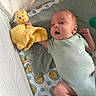 baby, baby_clothing, baby_sock, blanket, child, crib, cute, happy, indoors, infant, lying_down, mesh_crib, newborn, onesie, patterned_blanket, plush_toy, smiling, soft_lighting, toy, winnie_the_pooh