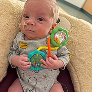 Anthony is registered to the contest to win money with this photo: baby, clothing, colorful, comfort, cushion, cute, expression, face, feeding_tube, hand, head, indoor, infant, medical, newborn, onesie, person, sitting, soft, toy