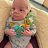 baby, clothing, colorful, comfort, cushion, cute, expression, face, feeding_tube, hand, head, indoor, infant, medical, newborn, onesie, person, sitting, soft, toy