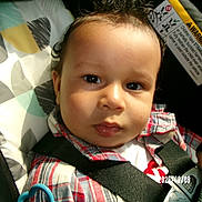 Omari joined the competition — help win amazing prizes! baby, child, car_seat, plaid_shirt, face, eyes, infant, seatbelt, safety, close_up, child_seat, clothing, young_child, indoors, cute, person, portrait, infancy, baby_toy, car_interior