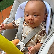 Jayden participe au concours pour gagner de l'argent avec cette photo : baby, child, high_chair, safety_harness, plush_toy, yellow_toy, bear_pattern, onesie, infant, outdoor, green_grass, terracotta_tiles, curious, cute, sitting, person, face, head, hand, soft_toy