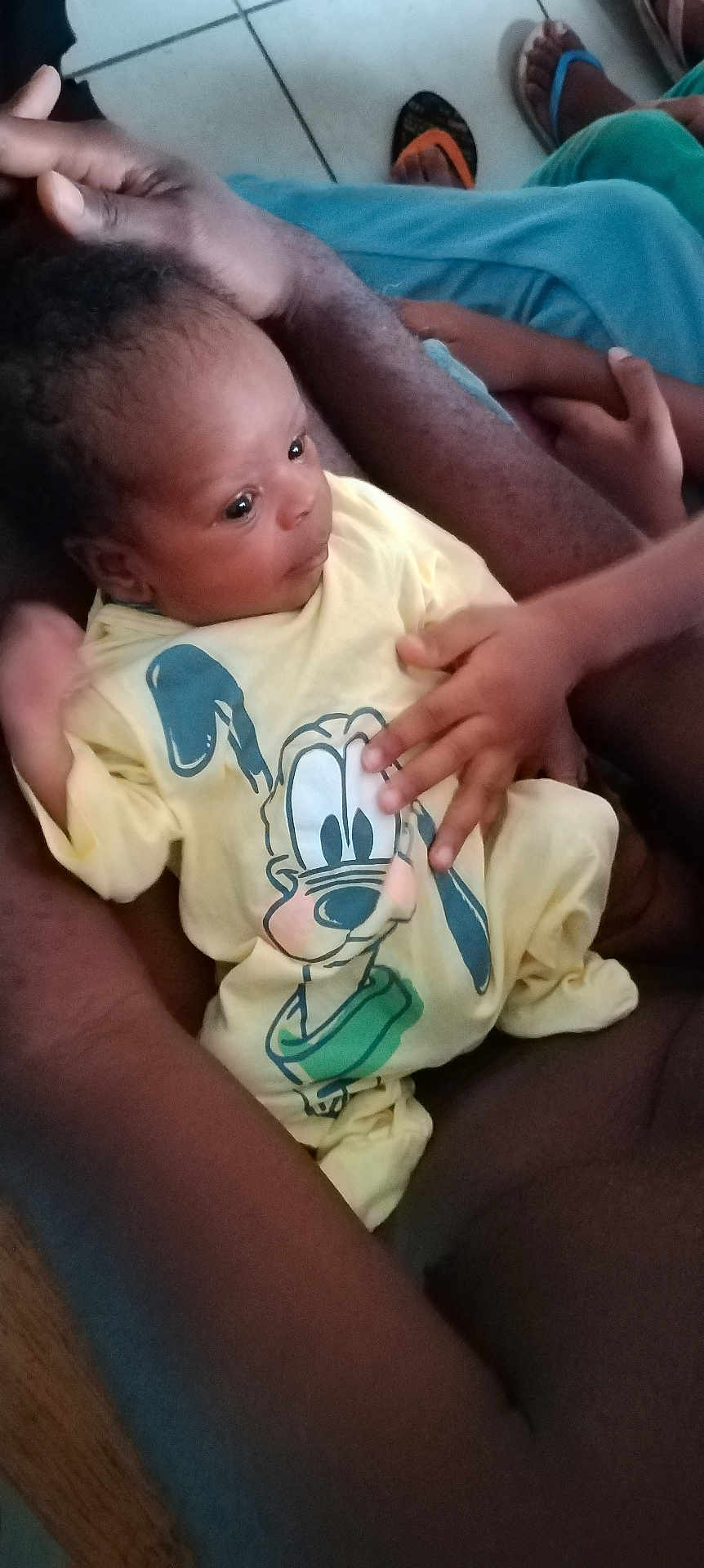 éliséo a rejoint le concours — aidez-le/la à gagner de superbes lots ! baby, child, infant, person, hand, arm, yellow_clothing, cartoon_print, floor_tile, footwear, flip_flops, holding, close_up, indoor, skin, cute, small_hand, sitting, family, care