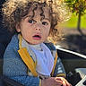 toddler, child, curly_hair, portrait, face, surprised, open_mouth, eyes, sunlight, outdoor, car, car_seat, jacket, yellow_clothing, blue_fleece, bib, hands, steering_wheel, greenery, close_up