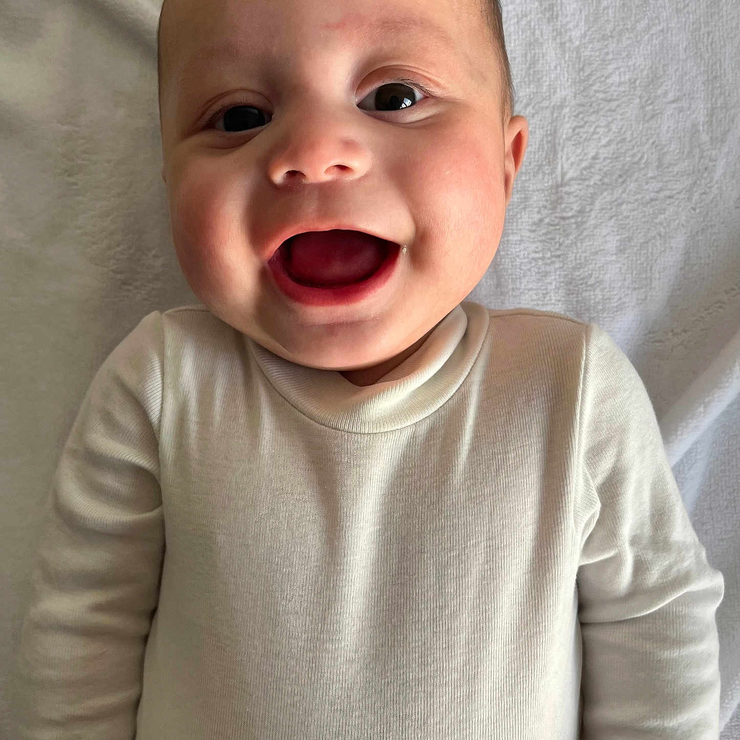 Taimanarii participe au concours pour gagner de l'argent avec cette photo : baby, big_eyes, blanket, cheeks, close_up, cute, ear, face, hands, happy, head, infant, lying_down, onesie, open_mouth, portrait, skin, smile, towel, white_clothing
