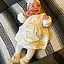 Marta participe au concours pour gagner de l'argent avec cette photo : baby, blanket, boots, child, cozy, cute, dress, floor, flower, happy, headband, indoor, infant, lying_down, patterned_blanket, person, portrait, smiling, toddler, white_clothing